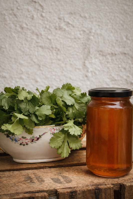 Tarro de miel de cilantro con hojas de cilantro.
