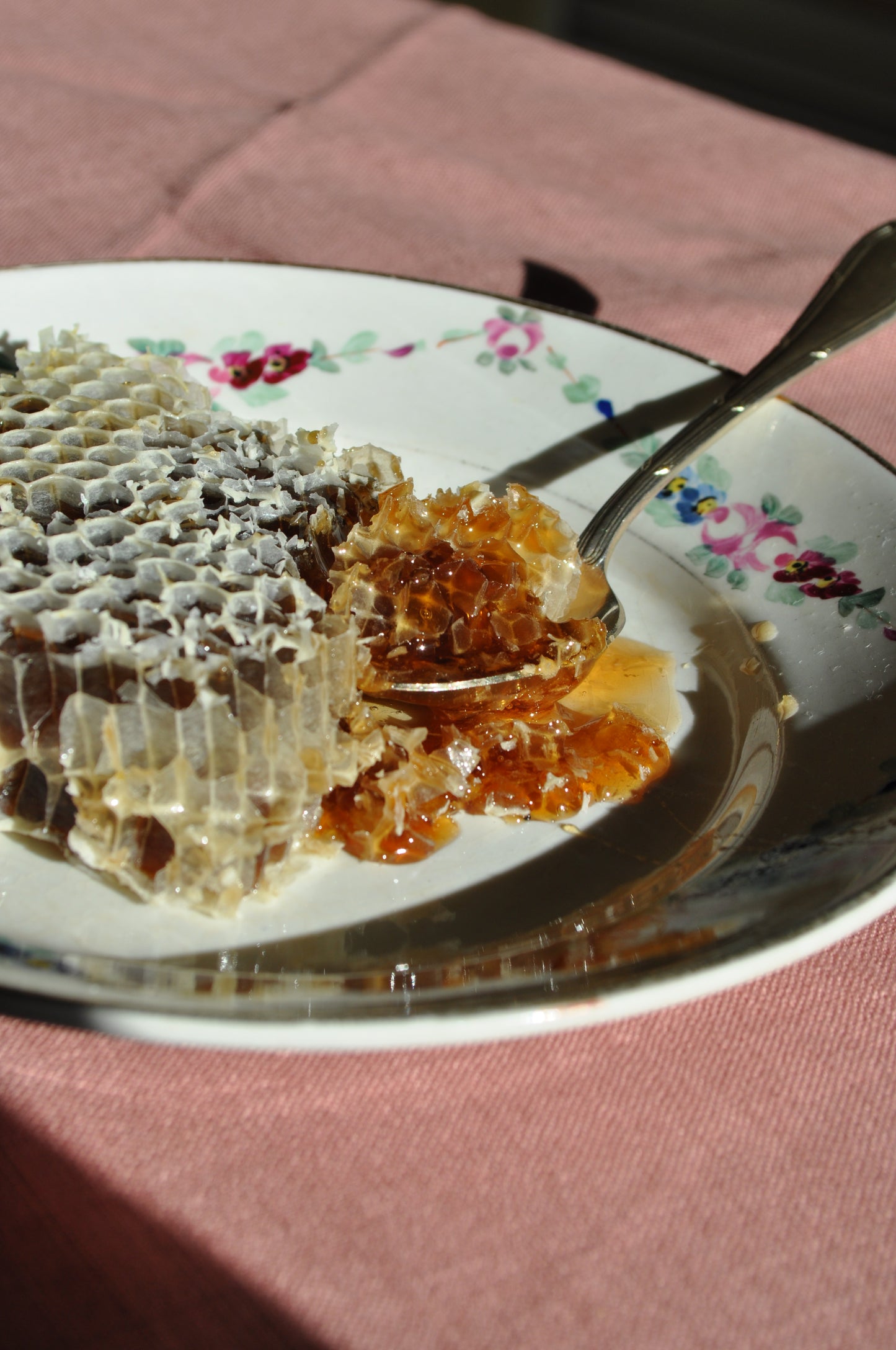 Plato de cerámica con panal y cuchara de plata en el desayuno