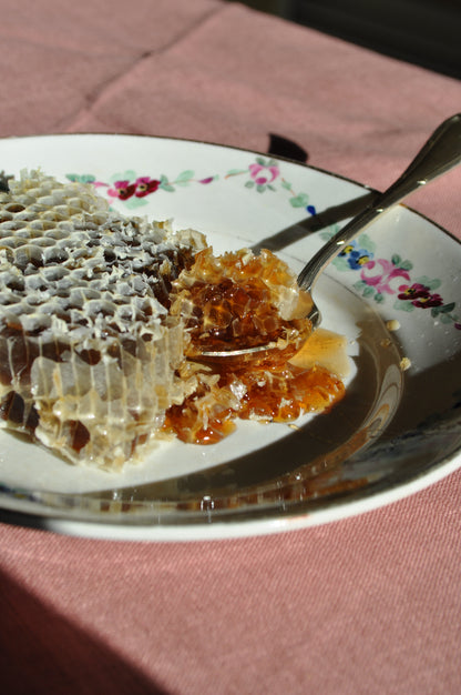 Plato de cerámica con panal y cuchara de plata en el desayuno